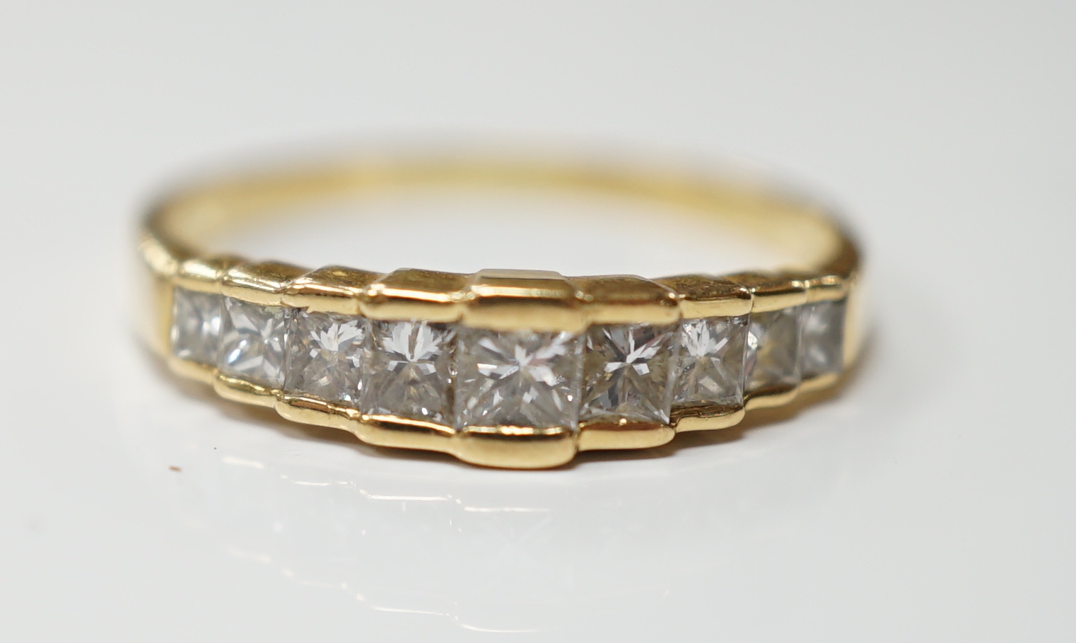 A modern 18ct gold and graduated nine stone princess cut diamond set half hoop ring, size L, gross weight 1.9 grams.